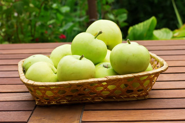 Fresh green apples in bucket on wooden surface
