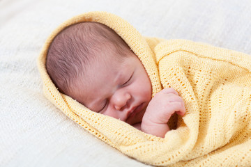 Obraz premium sleeping newborn baby wrapped in a yellow blanket