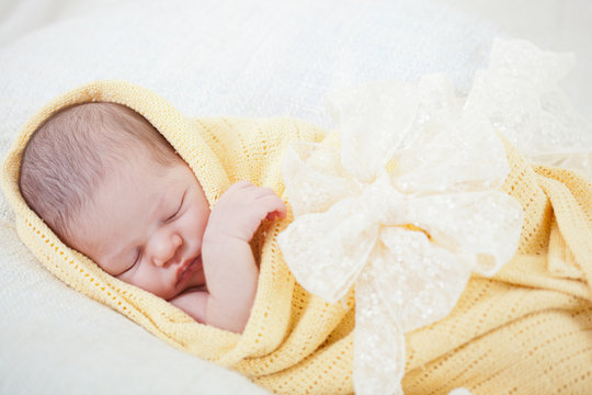 Sleeping Newborn Baby Wrapped In A Yellow Blanket
