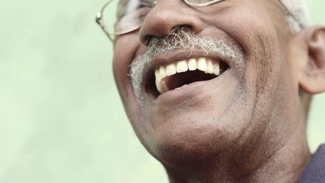 Old black man with glasses and mustache smiling