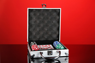 Poker set in metallic case on bright red background
