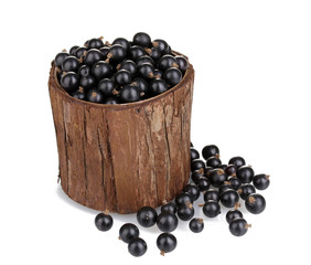 Black currant in wooden cup isolated on white