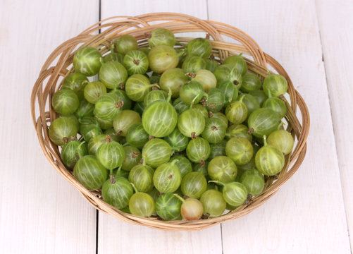 Green gooseberry in basket on wooden background