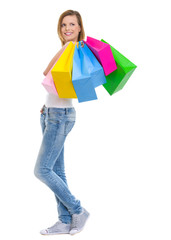 Smiling teenage girl with shopping bags looking on copy space