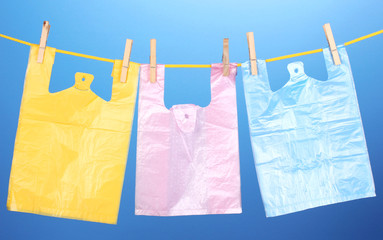 Cellophane bags hanging on rope on blue background