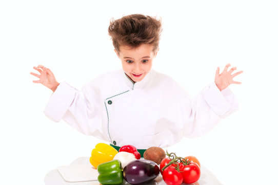 Little boy chef in uniform cooking vegatables