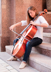 Woman playing cello on the stairway outdoors © Alexander Pekour