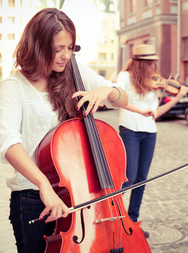 Two Women Strings Duet Playing Violin And Cello On The Street