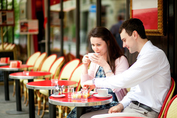 Happy couple drinking coffee in a Parisian outdoor cafe