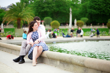 Fototapeta na wymiar Loving couple sitting by the water in Luxembourg garden of Paris