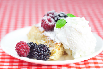 cake with icing,icecream, raspberry, blackberry and mint on a pl