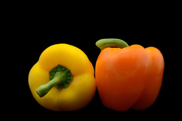 Pair of yellow and  red bell peppers isolated over black