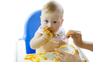 A young blue-eyed child feeding pumpkin puree