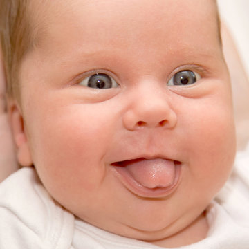 Newborn baby's face smiling and showing tongue