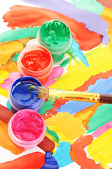 Jars with colorful gouache on a bright picture close-up