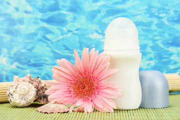 deodorant, flower and shells on blue sea background