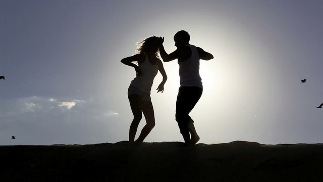 Romantic scene:  happy couple dancing over sun with flying birds