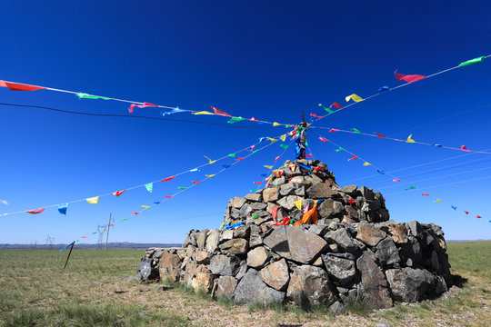 praying stone and prayer flags on steppe