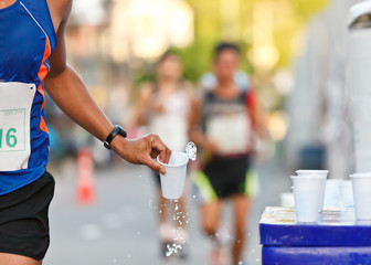 Marathon racer catching cup of water - 43666588