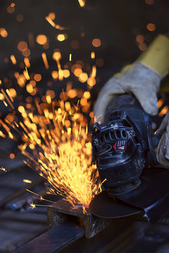 Worker cutting metal with many sharp sparks