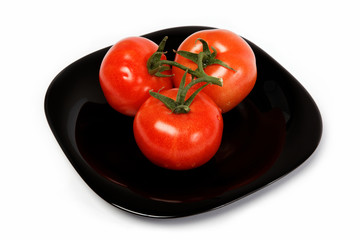 Fresh tomatoes on a plate, isolated on a white background.