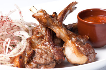 Grilled meat on the ribs and onion with sauce
