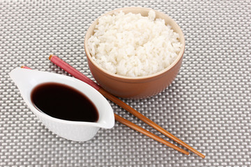 Bowl of rice and chopsticks on grey mat