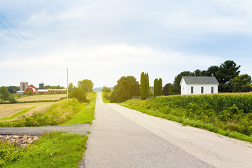 Fototapeta na wymiar Country Road With Red Farm and Church