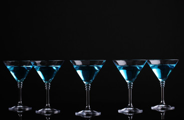 Blue cocktail in martini glasses isolated on black