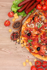 delicious pizza, vegetables and salami on wooden table