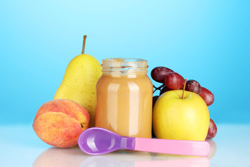 Jar with fruit baby food and spoon on colorful background