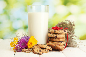 glass of milk, chocolate chips cookies with red ribbon and