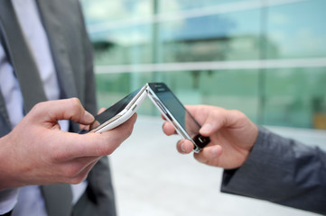 Closeup on mobile phones hold by business people