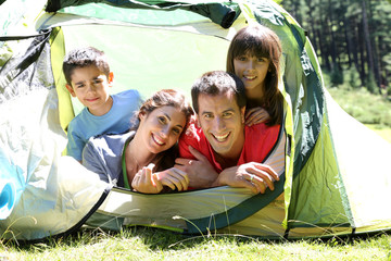 Portrait of family laying in camp tent