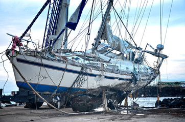  Storm-damaged yacht on Easter Island in the Pacific Ocean. Hole in the hull of a boat after a...
