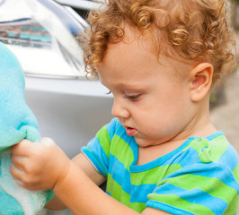 a little boy washing the car with a sponge