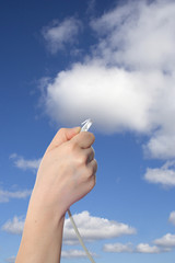 Conceptual human hand holding a internet data cable in clouds