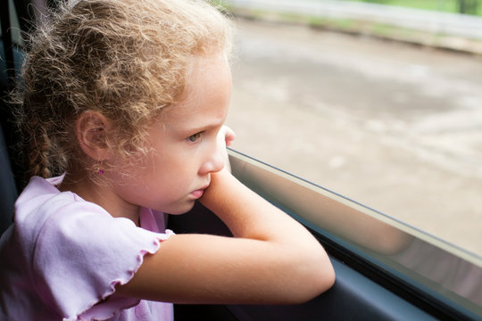 Sad Little Girl Sitting Near The Window In The Car