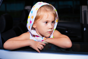 sad little girl sitting near the window in the car