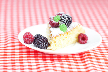 cake with icing, raspberry, blackberry and mint on a plate on pl