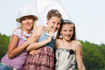 three happy young girl friends under umbrella