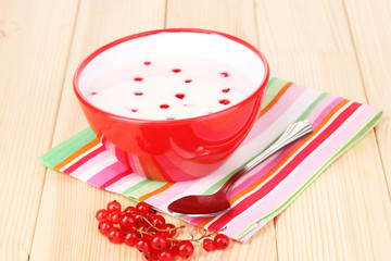 Yogurt with redcurrant on wooden table
