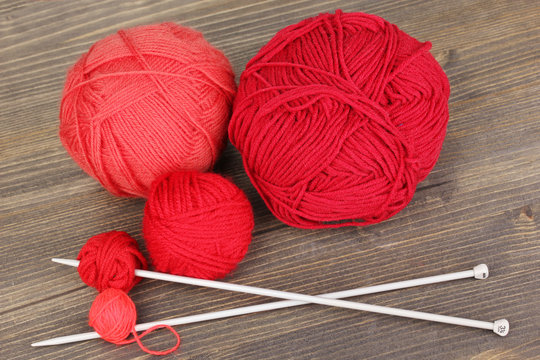 Red knittings yarns on wooden table close-up