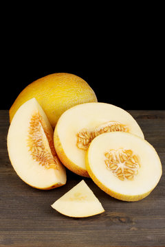 Cut ripe melons on wooden table on black background