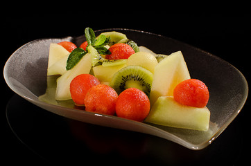 Red and yellow melon salad on a transparent glass plate.