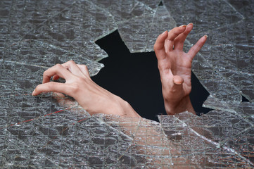 Two hands make their way through the broken glass