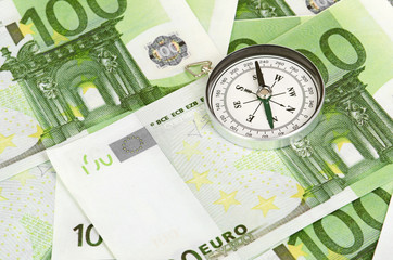 many euro bank notes and a compass