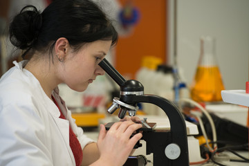 Young woman works with microscope