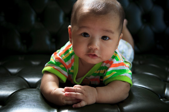 face of baby lied on sofa bed with eyes contact