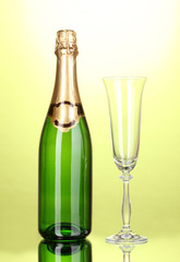 Bottle of champagne and goblet on green background